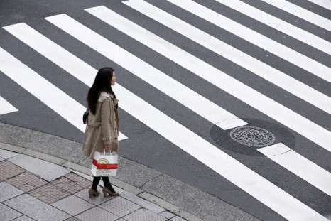 A woman holds a shopping bag as she waits at a pedestrian crossing in the Ginza district in Tokyo, Japan, March 24, 2016. 