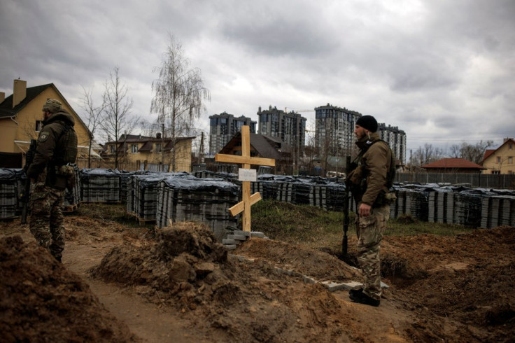 Ukrainian soldiers stand next to the grave of a civilian, who according to residents was killed by Russian soldiers, amid Russia's invasion of Ukraine, in Bucha, Kyiv region, Ukraine, April 6, 2022. 