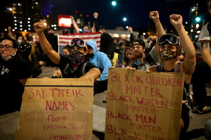 Demonstrators wearing protective face masks raise their fists as they sit in silence for nine minutes in a peaceful protest against the death in Minneapolis police custody of George Floyd, at 19th and Broadway in Denver, Colorado, U.S., June 1, 2020.