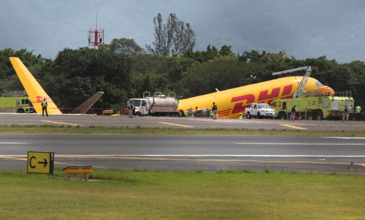 Firefighters work at the scene where a Boeing 757-200 cargo aircraft operated by DHL made an emergency landing before skidding off the runway and splitting, aviation authorities said, at the Juan Santamaria International Airport in Alajuela, Costa Rica Ap