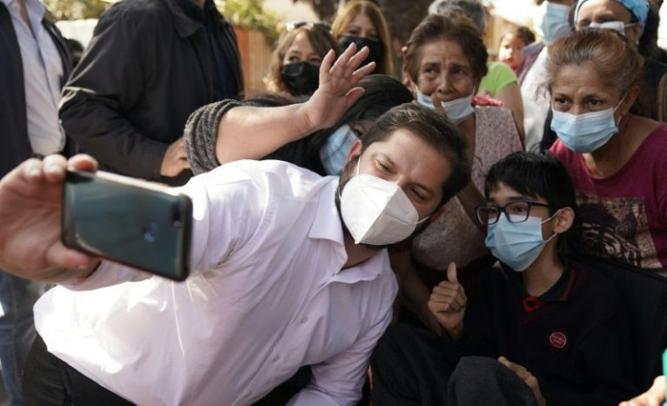 Chilean President Gabriel Boric takes a selfie with supporters during a political rally in Santiago, on April 07, 2022
