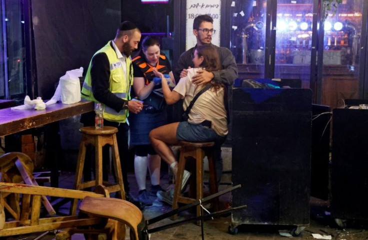 First responders tend to a woman in the aftermath of a shooting attack in the centre of Israel's Mediterranean coastal city of Tel Aviv on April 7, 2022