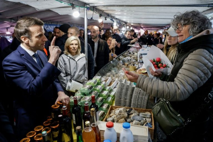 Macron bought flowers for his wife during an impromptu visit to a market Friday as he works on on his image ahead of voting.