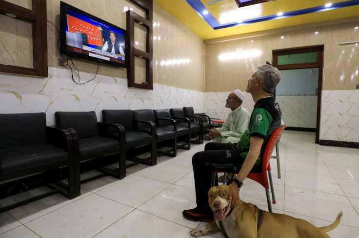 People watch the speech of Pakistani Prime Minister Imran Khan on a television screen, in Peshawar, Pakistan, April 8, 2022.