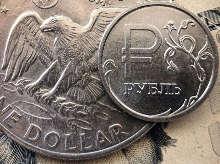 A Russian ruble coin is pictured with US dollar bills and a one dollar coin in Moscow, on March 15, 2022