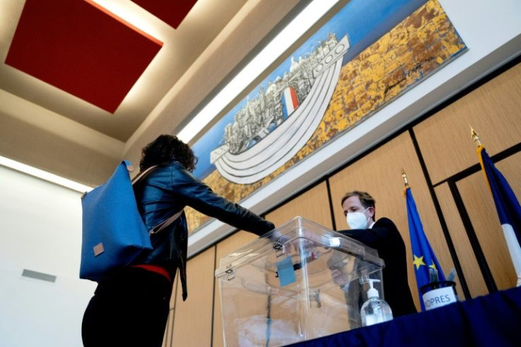 A voter puts her ballot for the French presidential election into the ballot box in Washington, on April 9, 2022