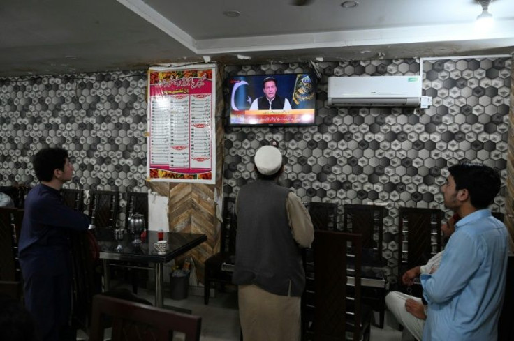 People listen to Pakistan's Prime Minister Imran Khan addressing the nation on television at a restaurant in Islamabad on April 8, 2022, one day before he was ousted by a no-confidence vote