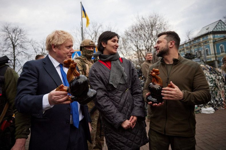 Ukraine's President Volodymyr Zelenskiy and British Prime Minister Boris Johnson hold ceramic roosters presented by local women, the same that were found among debris of residential building destroyed during Russia's invasion, in Borodianka town, central 