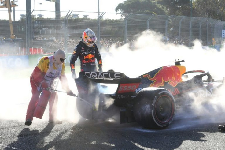 A marshal wields a fire extinguisher as Max Verstappen looks on after his Red Bull retired on lap 40 at Albert Park