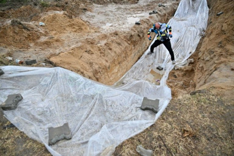 A worker moves the plastic cover over a mass grave in the Ukrainian city of Bucha, near Kyiv, on April 9, 2022