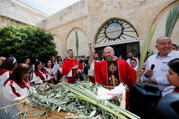 Father Rami Asakriyah sprinkles holy water on palm fronds during the Palm Sunday service at the Church of the Nativity in Bethlehem, in the Israeli-occupied West Bank, April 10, 2022.