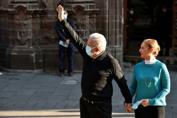 Mexican President Andres Manuel Lopez Obrador, accompanied by his wife Beatriz Gutierrez, waves after attending a polling station in Mexico City for a presidential recall referendum