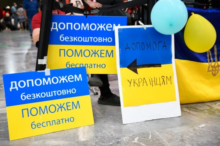 Volunteers with signs welcome Ukrainian refugees as they arrive at the Tijuana, Mexico airport on their way to the US