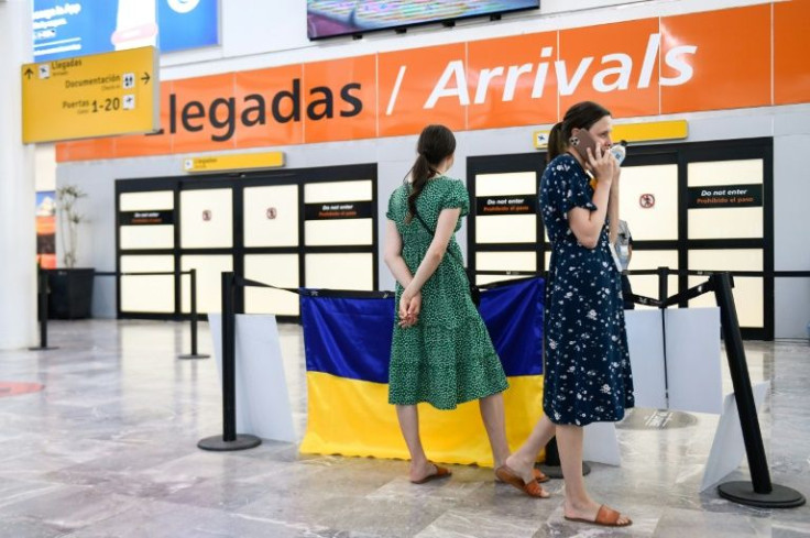 Volunteers Liza Melnichuk (C) and Maria Melnichuk, 26-year-old twins, wait at an arrival area at the Tijuana airport to welcome arriving Ukrainian refugees