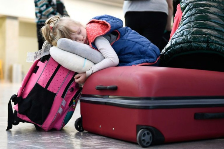 Three-year-old Anna Kuts sleeps on a suitcase after arriving with her family at the Tijuana, Mexico airport, where an army of volunteers is helping Ukrainian refugees near the end of their long voyage to the United States