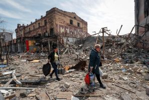 Residents carry their belongings near buildings destroyed in the course of Ukraine-Russia conflict, in the southern port city of Mariupol, Ukraine April 10, 2022. 
