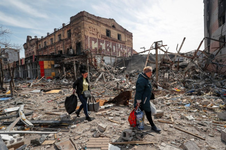 Residents carry their belongings near buildings destroyed in the course of Ukraine-Russia conflict, in the southern port city of Mariupol, Ukraine April 10, 2022. 