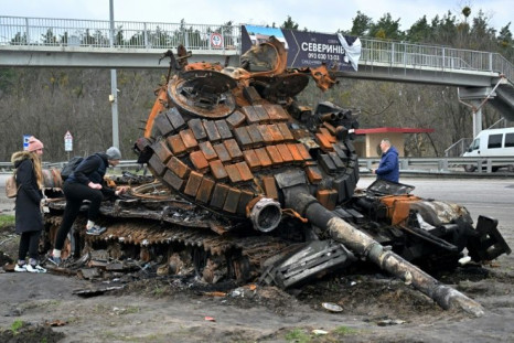 Residents near the town of Buzova, west of Kyiv, examine the wreckage of a Russian tank on April 10, 2020