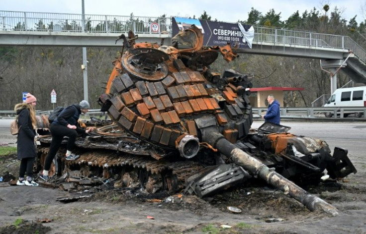 Residents near the town of Buzova, west of Kyiv, examine the wreckage of a Russian tank on April 10, 2020