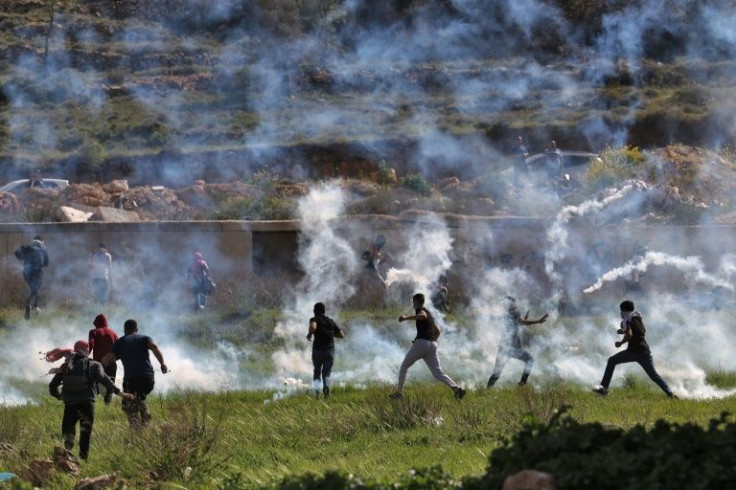 Palestinians run for cover during clashes with Israeli security forces at the northern entrance of Ramallah, near the Israeli settlement of Beit Eil, in the occupied West Bank, on April 11, 2022