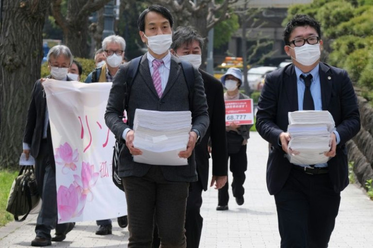 Hiroki Ishiguro (R), a lawyer who has represented technical interns, walks to the Supreme Court in Tokyo to submit an appeal and signed petitions for acquittal of Vietnamese technical intern trainee Le Thi Thuy Linh