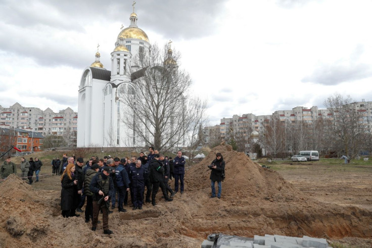French forensics investigators, who arrived to Ukraine for the investigation of war crimes amid Russia's invasion, stand next to a mass grave in the town of Bucha, in Kyiv region, Ukraine April 12, 2022.  