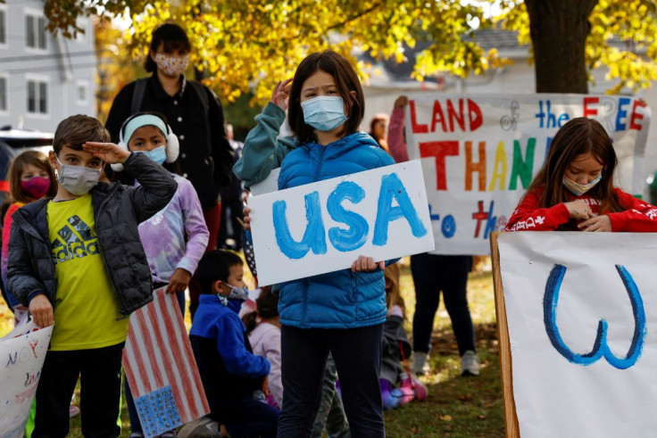 Children wearing protective face masks stand holding signs during a Veterans Day ceremony at the John Philip Sousa Memorial Bandshell at Sunset Park in Port Washington, New York, U.S. November 11, 2021. 
