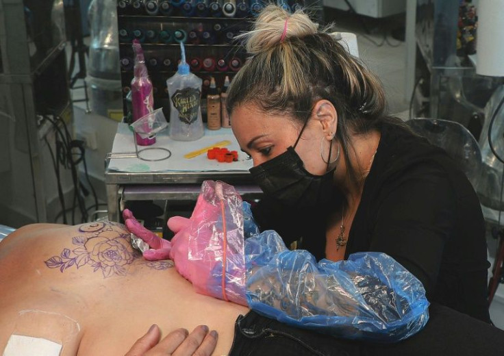 Brazilian tattoo artist Karlla Mendes works on Marlene Silva dos Santos, who has scars from cancer surgery on her left breast, as part of the 'We are Diamonds' project, in Sao Paulo, Brazil