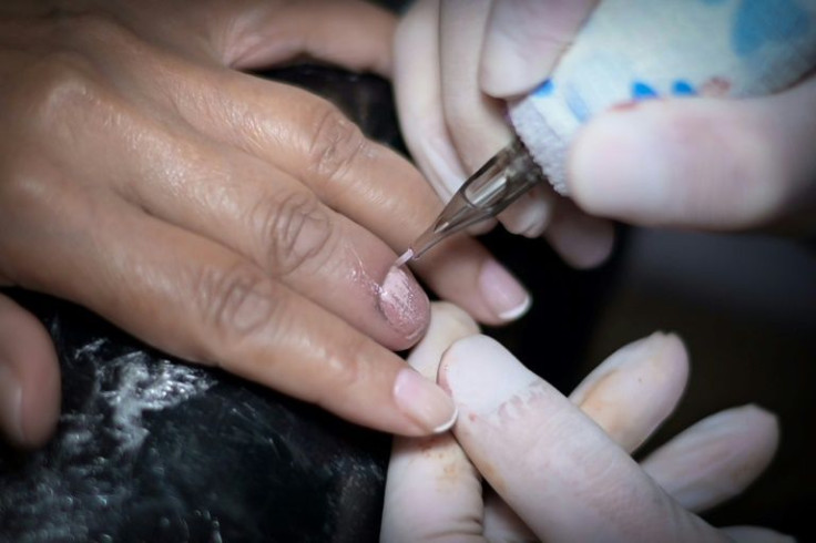 Brazilian tattoo artist Augusto Molinari works on Dulcineia Soares, a keyboardist who as a child lost a part of her finger