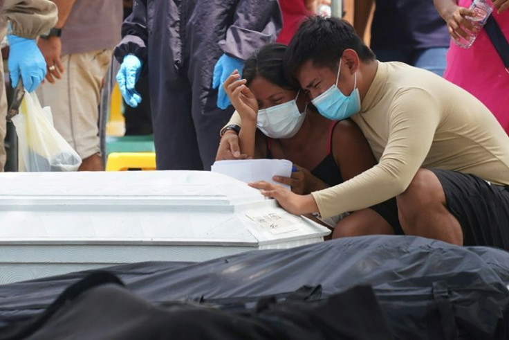 Residents cry in front of a coffin and a body bag as they mourn their dead relatives, victims of a landslide that devastated Pilar village in Abuyog town, Leyte province