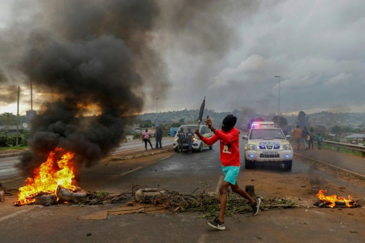 A resident of Bhambayi runs past burning tyres during a protest for water and electricity to be restored after the storm
