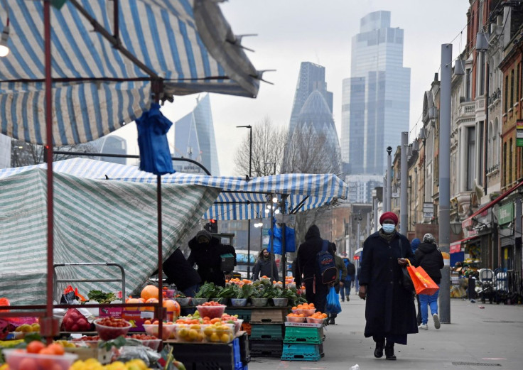 People shop at market stalls, with skyscrapers of the CIty of London financial district seen behind, amid the coronavirus disease (COVID-19) pandemic, in London, Britain, January 15, 2021. 