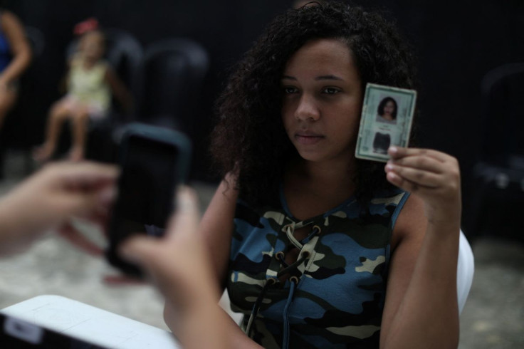 17-year-old Vitoria Rodrigues de Oliveira takes a photo of a young woman to register her to vote for Brazil?s upcoming elections in Sao Joao de Meriti in Rio de Janeiro state, Brazil April 5, 2022.