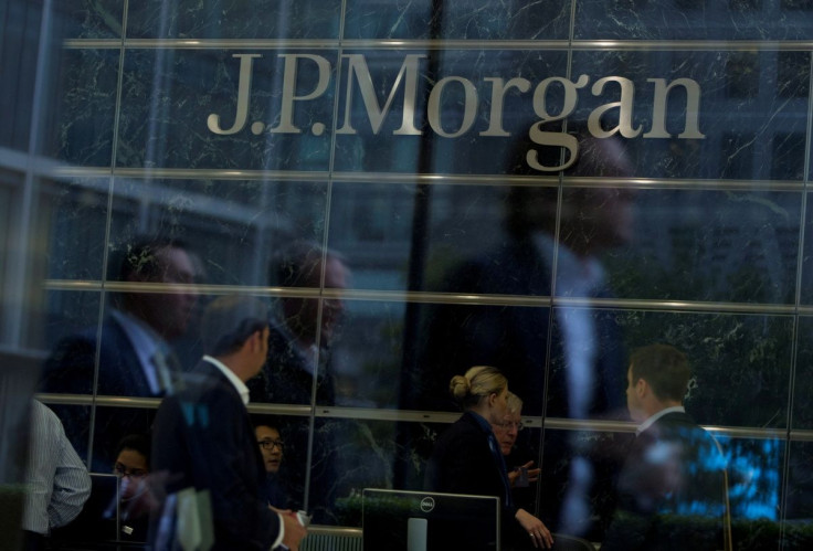 Workers are reflected in the windows of the Canary Wharf offices of JP Morgan in London September 19, 2013. 