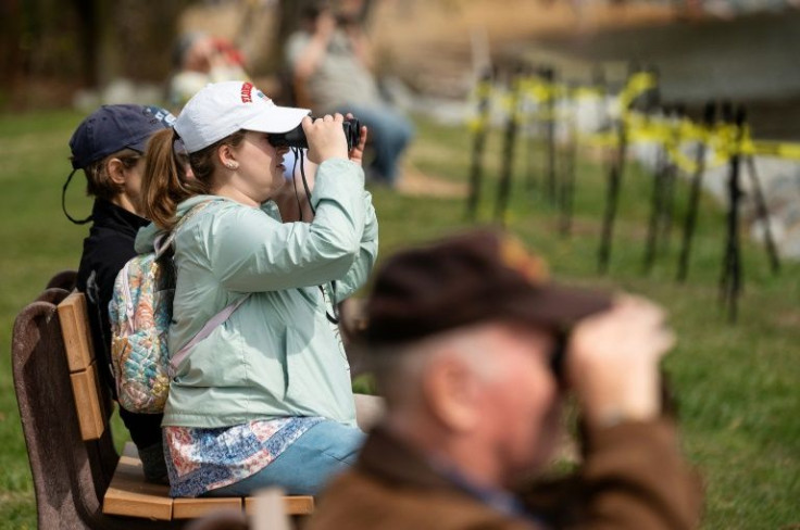Onlookers use binoculars to watch cranes take containers off the Ever Forward container ship, from Downs Park in Pasadena, Maryland on April 13, 2022
