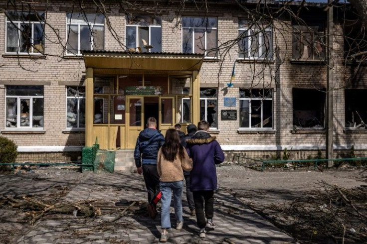 Youths walk near a damaged school in Bohdanivka village, northeast of Kyiv