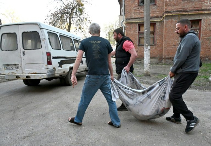 A communal worker and neighbours carry in a rug the body of a 38 year-old resident who was killed when a missile exploded in a residential area of Kharkiv on April 15, 2022