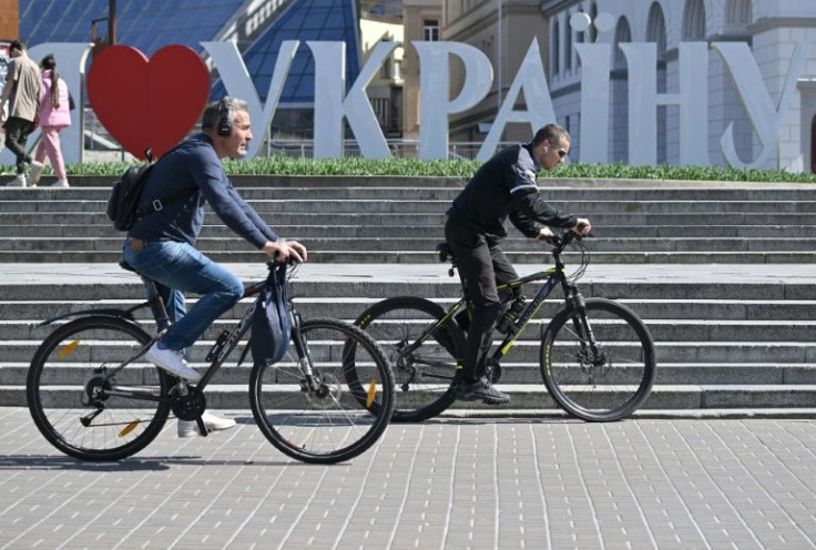 Cyclists ride in front of the installation reading 'I love Ukraine' on Independence Square