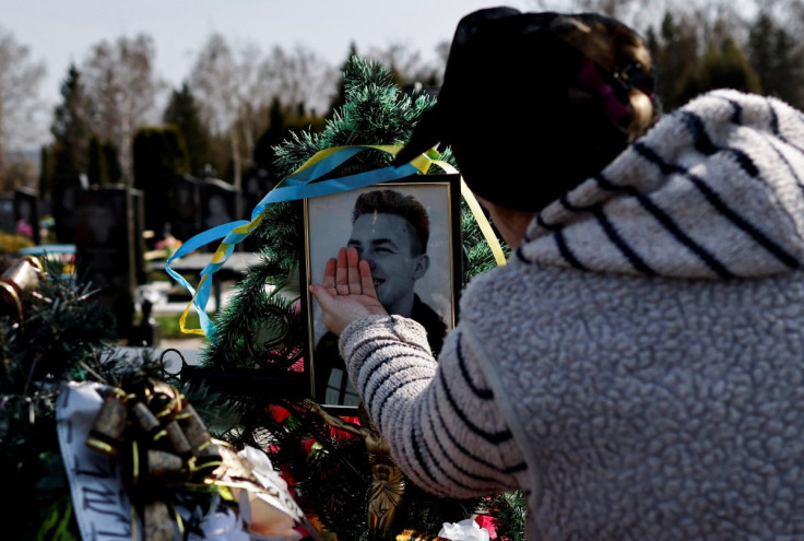 Natalia Evdokimova, 46, touches a photograph of her son Dmytro Evdokimov, 23, who was killed in a battlefield near Izium in Kharkiv region, as she mourns him beside his grave at the cemetery in Trostianets, Sumy region, Ukraine April 16, 2022.