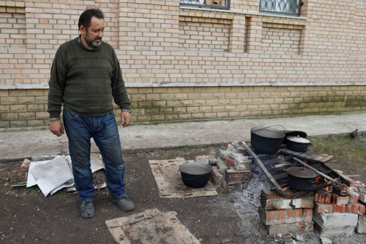A local resident prepares food on a street, as Russia's attack on Ukraine continues, in Sievierodonetsk, Luhansk region, Ukraine April 16, 2022.  