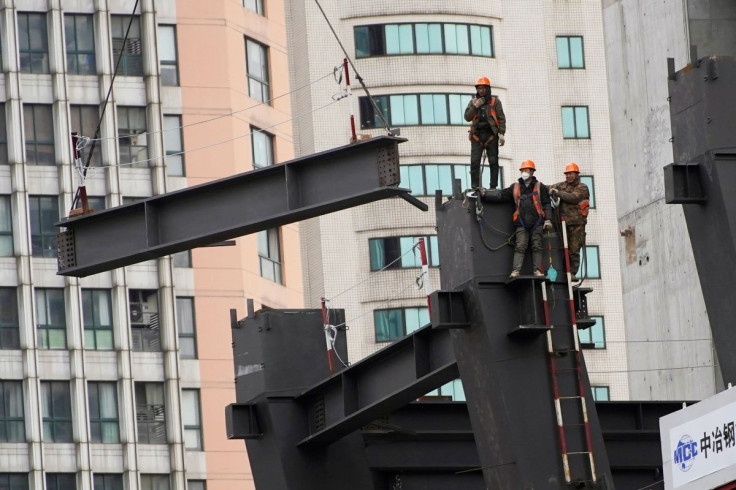 Workers watch as a crane lifts a structure at a construction site in Shanghai, China January 14, 2022. 