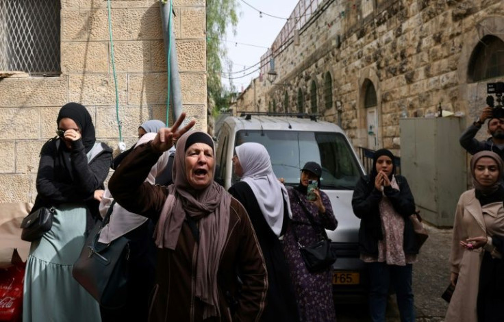 A Palestinian woman gesticulates as Israeli  police (unseen) patrol in front of Lion's Gate in Jerusalem's Old City