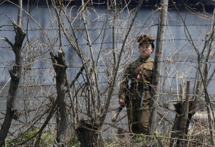 A North Korean prison policewoman stands guard behind fences at a jail on the banks of Yalu River near the Chongsong county of North Korea