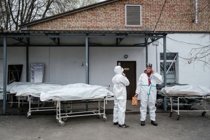 Workers take a break next to body bags as they exam the bodies of victims at a morgue in Bucha, on April 19, 2022, during the Russian invasion of Ukraine