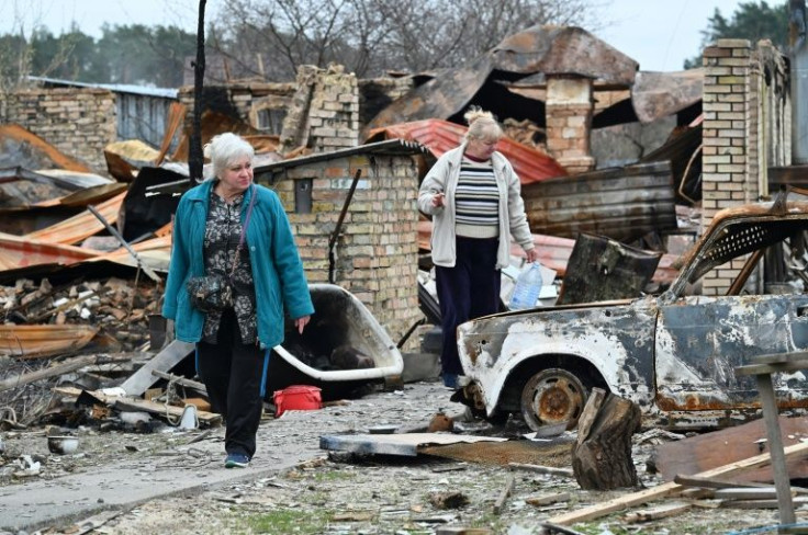 Nadiya (L), and Natalia (R), both 62, walk amid debris of their destroyed houses in the village of Moshchun, northwest of Kyiv