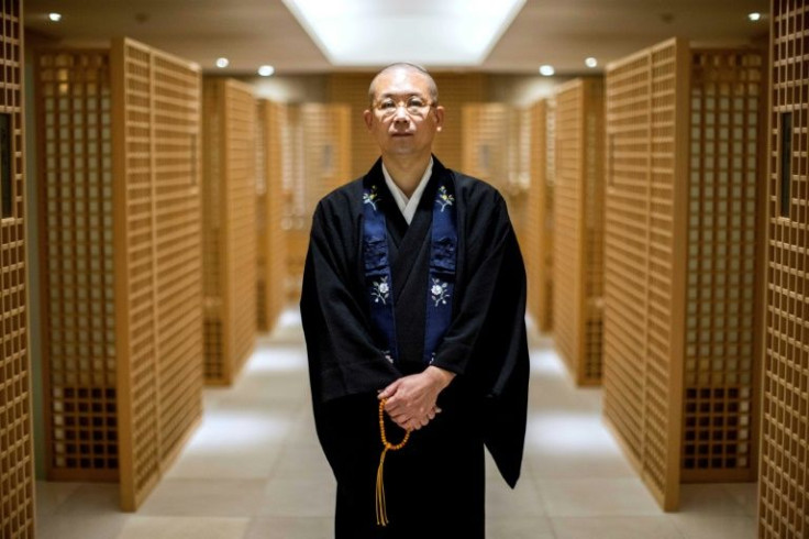 Tomohiro Hirose, resident monk of Kuramae-ryoen facility, a multi-storey charnel house and Buddhist temple, poses while flanked by mourning booths where visitors can pray for their departed loved ones in front of urns containing their ashes