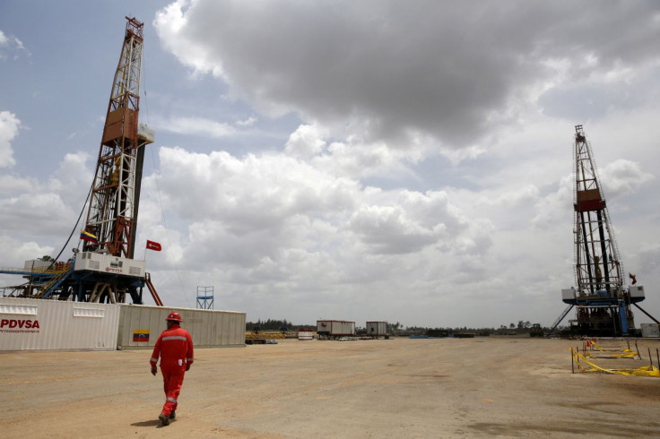 An oilfield worker walks next to drilling rigs at an oil well operated by Venezuela's state oil company PDVSA, in the oil-rich Orinoco belt, April 16, 2015.. 