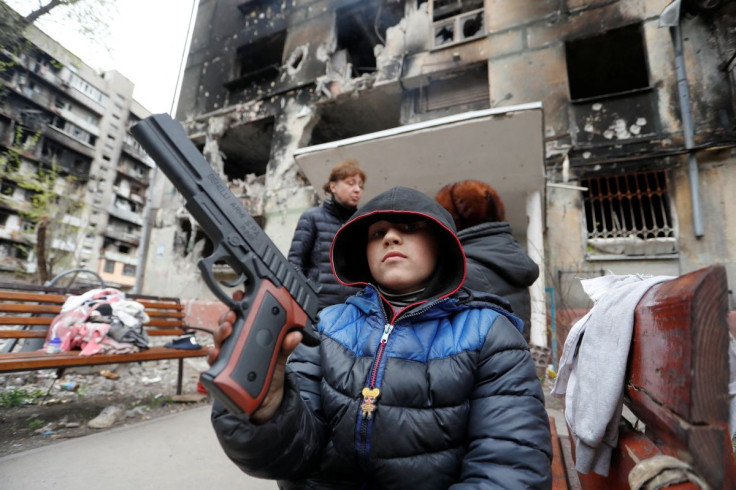Local resident Sasha, 8, holds a toy gun in front of a residential building heavily damaged during Ukraine-Russia conflict in the southern port city of Mariupol, Ukraine April 21, 2022. 