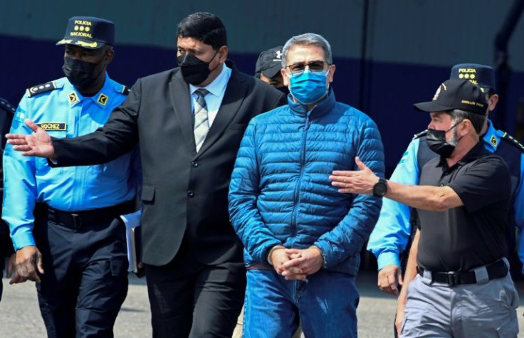 Honduras' former President Juan Orlando Hernandez (2-R) is escorted by Minister of Security Ramon Sabillon (R) towards a plane of the US Drug Enforcement Agency (DEA), during his extraditaton to United State at the Air force Base, in Tegucigalpa, on April