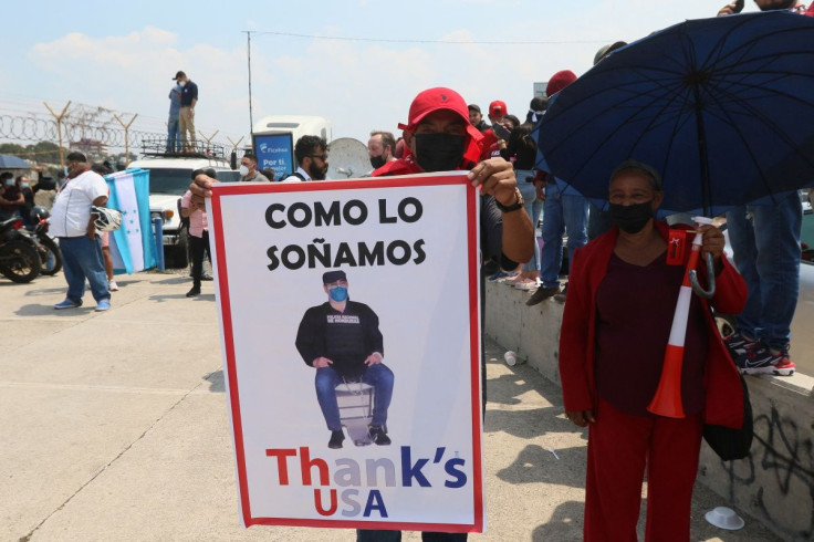 Supporters of Honduran President Xiomara Castro, one of them holding a sign with a photo of Honduras former President Juan Orlando Hernandez, stand outside the Toncontin International Airport as Hernandez is being extradited to the United States to face a